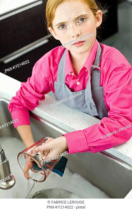 Portrait of a girl washing a measuring jug at a sink