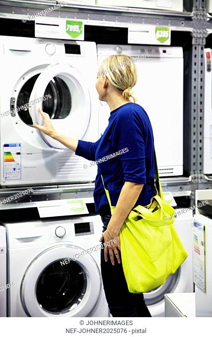 Woman looking at washing machine in shop