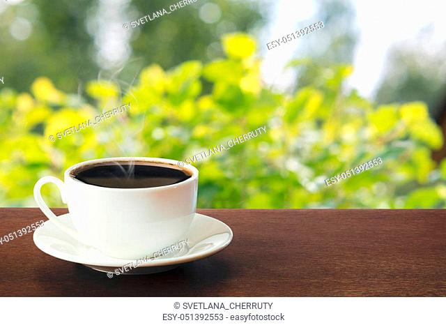Hot cup of black coffee in a sunny day on tabletop. Summer. Outdoors. Close up