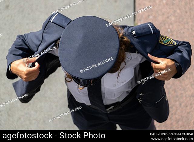 29 September 2023, Saxony, Dresden: A policewoman puts on her jacket in front of the Palace of Culture before the ceremonial appointment of 213 commissioners of...