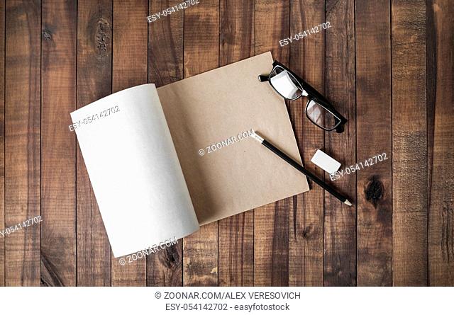 Blank notepad and stationery: glasses, pencil and eraser on wooden background. Flat lay