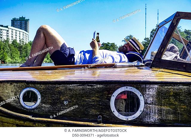 A man relaxes on his wooden boat in the Jarla Sjon a freshwater lake, part of the Sickla lock system, which joins the Baltic Sea with the Sickla and Jarla...