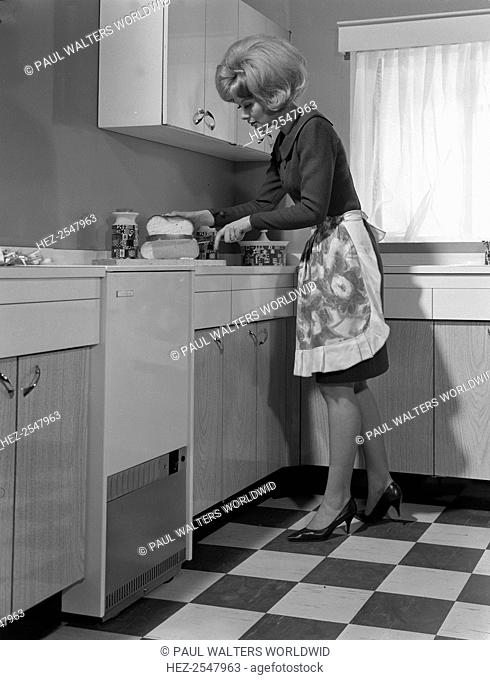 Kitchen scene, Warwick, Warwickshire, 1966. A model is seen at work in the kitchen in this photograph for a press advertisement for a boiler manufacturer
