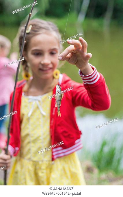 Germany, Girl with rod and small fish