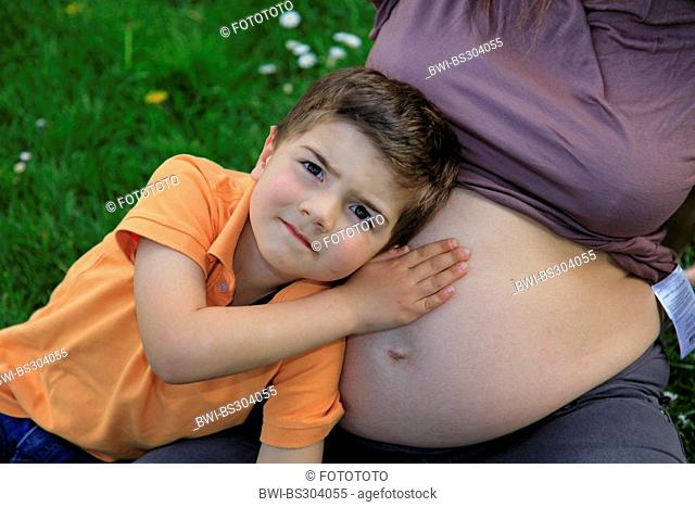 little boy leaning against the belly bump of his mother