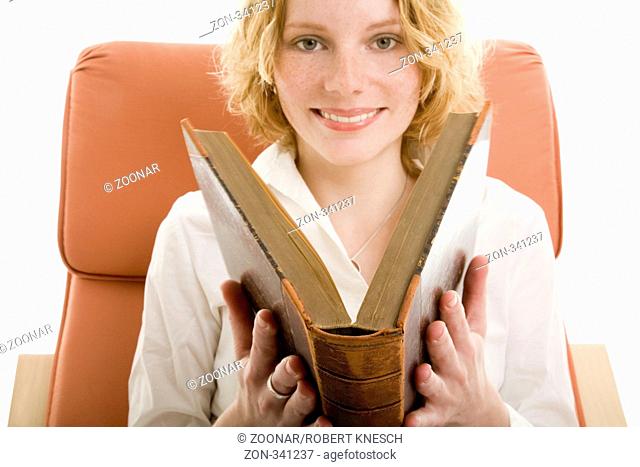 Fröhliche junge Frau klappt ein altes Buch zu