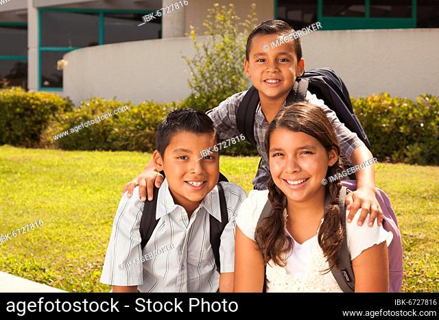 Young hispanic student children wearing backpacks on school campus
