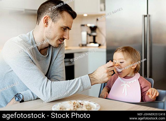 Father feeding toddler daughter