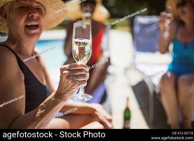 Happy senior woman drinking champagne with friends on summer patio