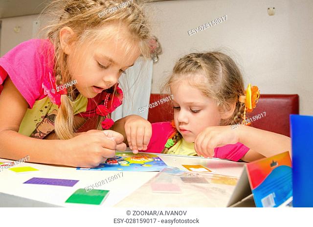Two girls on the train sitting at the table on the lower second-class place car and enthusiasm make applique
