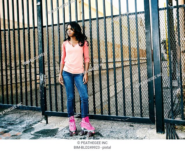 Black woman wearing roller skates near metal gate