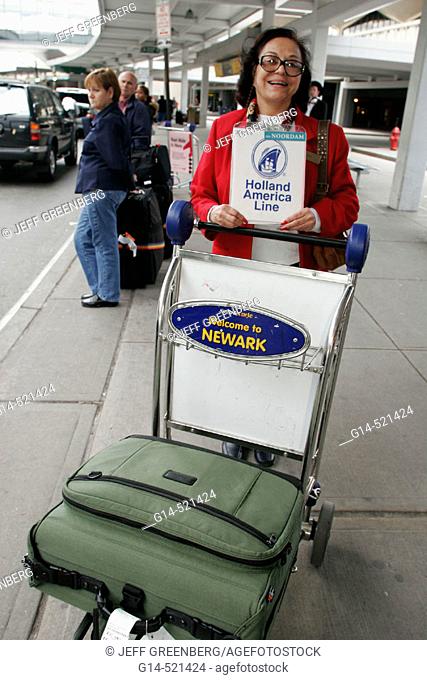Hispanic woman, sign, Holland America Line representative, luggage cart. Newark airport. New Jersey, USA