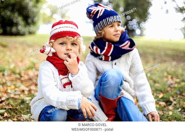 Portrait of blond little boy and his brother in the background wearing fashionable knit wear in autumn
