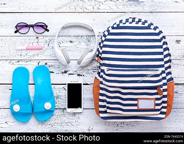 Summer holidays memories from beach with bag, earphones, flip flops, sunglasses and lip gloss. All summer objects are on the wooden background