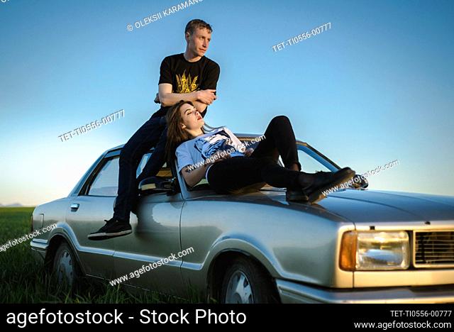 Ukraine, Crimea, Couple sitting on old fashioned car in rural scenery