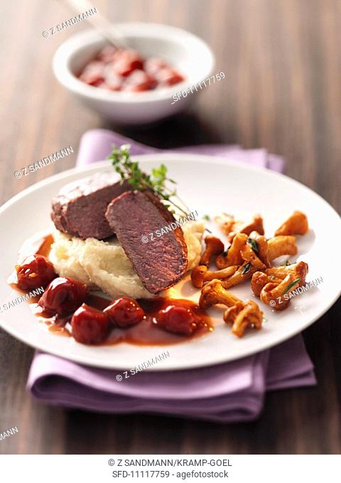 Venison steak on apple mashed potatoes with cherry sauce and chanterelle mushrooms