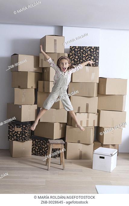 little girl jumping in front of lots of removal boxes