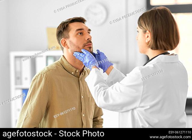 doctor checking lymph nodes of man at hospital