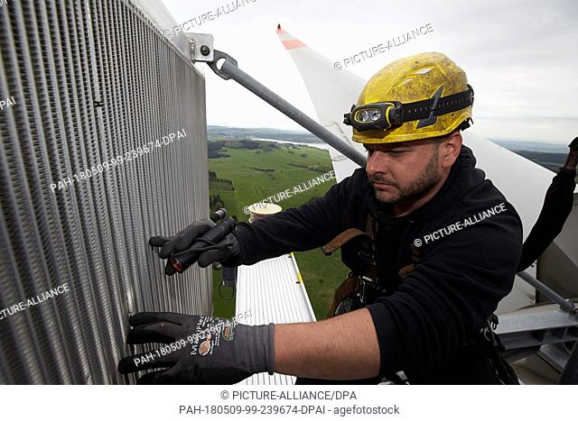 24 April 2018, Germany, Driedorf: Controller Christoph Lober checking the cooler on the roof of a wind turbine. The machines