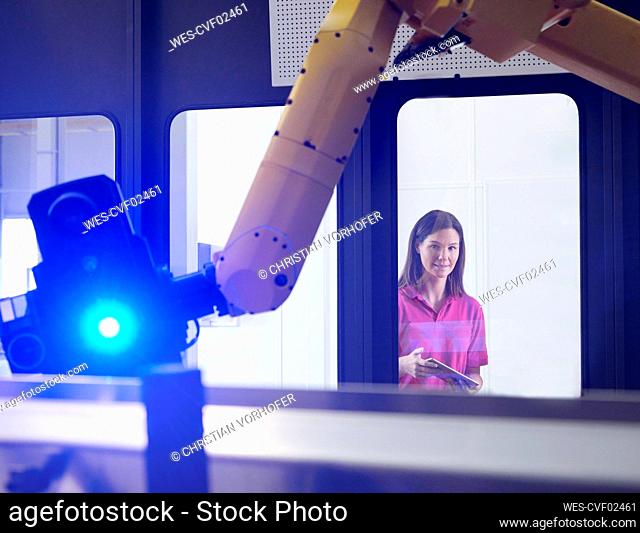 Engineer examining illuminated robotic arm in factory