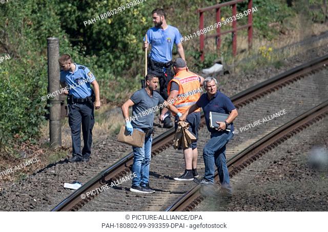 02 August 2018, Hessen, Sinn: A CID officer hands a brown paper bag to a colleague. Last week, a worker found a skeletonized arm on a part of the track that is...