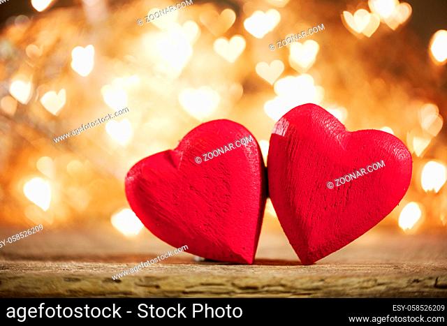 Two red wooden hearts symbol of love on background with beautiful bokeh party lights, Saint Valentine Day celebration