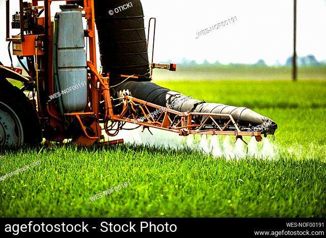 Crop sprayer sprinkling fertilizer on agricultural field
