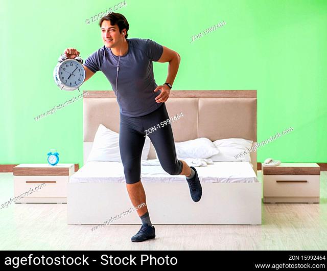 The young handsome man doing morning exercises in the hotel room