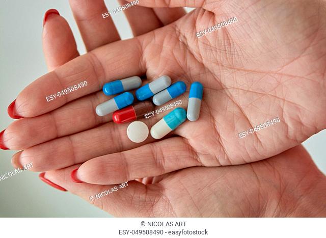 Colored assorted pharmaceutical medicine pills, tablets and capsules on female hand isoleted on white background. Close-up
