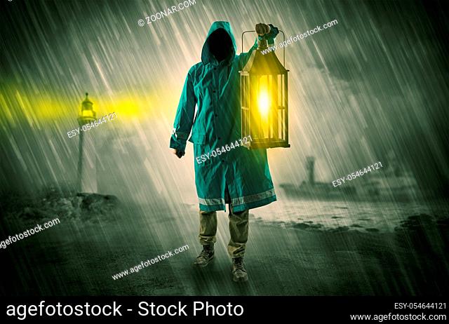 Man at the coast coming in raincoat with glowing lantern concept