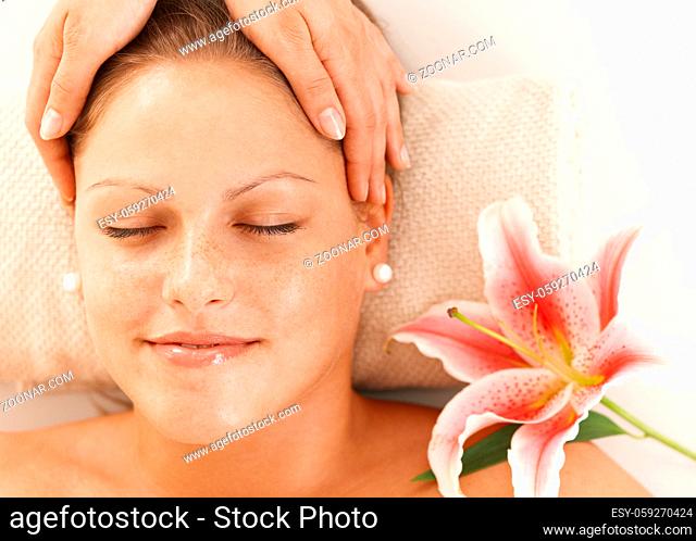 Closeup of portrait of young woman getting relaxing head massage, smiling