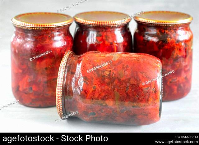 Home preservation: in glass jars, beets, canned with tomatoes, onions, carrots for cooking borscht, closed with a metal lid. Front view