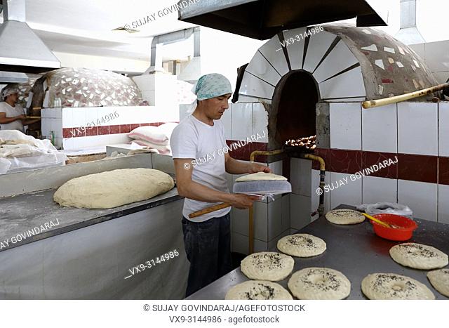 Tashkent, Uzbekistan - May 01, 2017: Uzbek man preparing regional style wheat bread in a local hotel