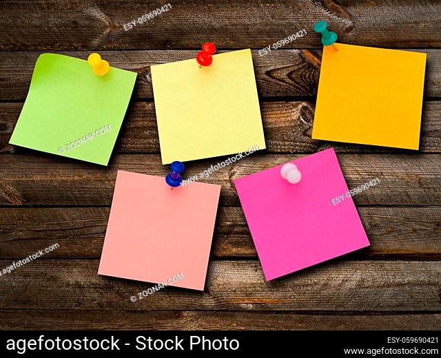Multicolored stickers and notes and drawing pins at the wooden background