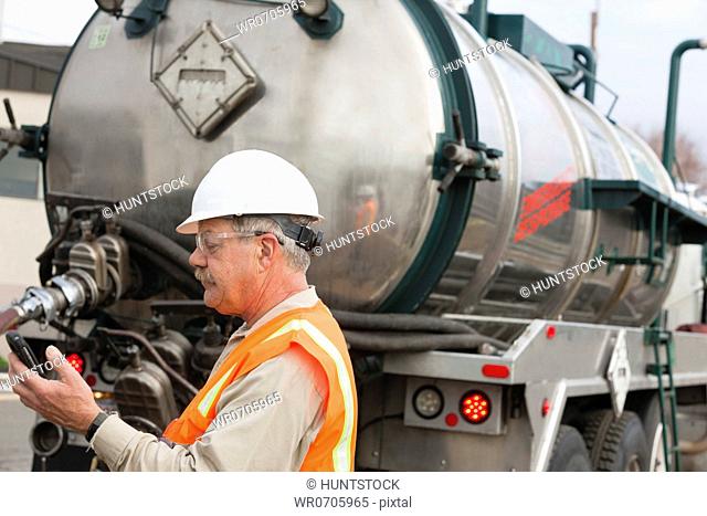 Environmental engineer on cell phone with tank truck at hazardous waste cleanup site