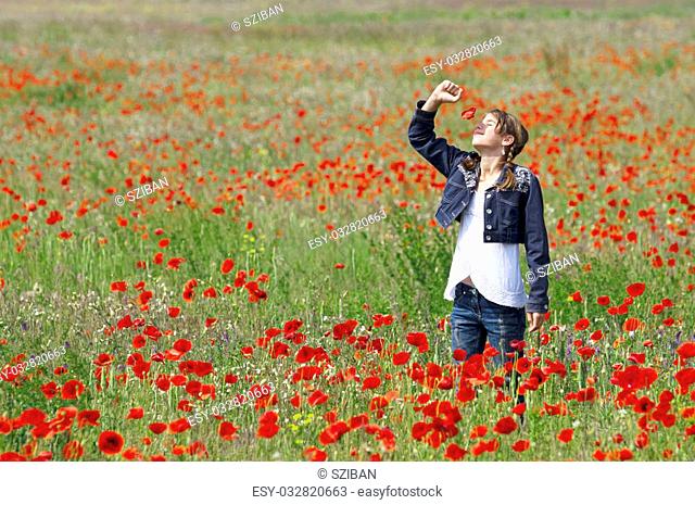 Girl on the meadow posing with lots of red poppies around her