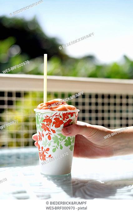 USA, Hawaii, Big Island, Pepeekeo, hand holding paper cup of fruit smoothie
