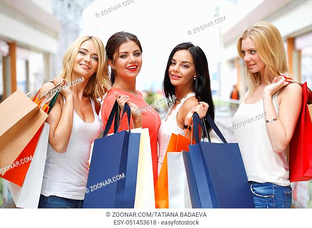 Young beautiful happy women showing shopping bags in mall