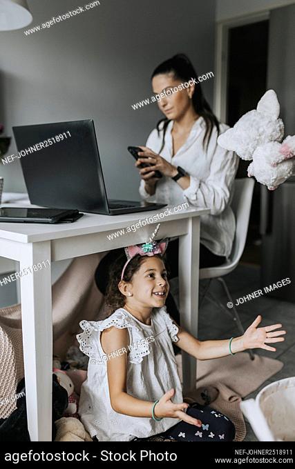 Girl playing while her mother working