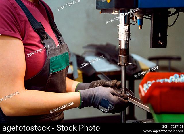 woman wearing a face mask due to coronavirus pandemic while working in the modern metal industry and using a drill. High quality photo