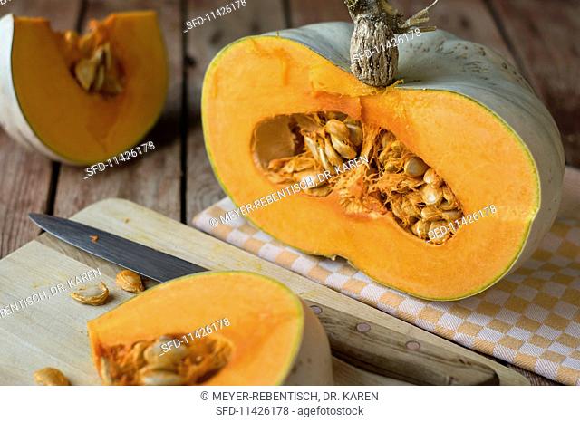 A sliced Crown Prince pumpkin on a rustic table with a yellow checked cloth