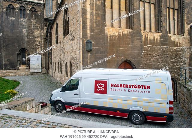 24 October 2019, Saxony-Anhalt, Halberstadt: A delivery van of the Halberstadt bakers and confectioners stands in front of the Halberstadt cathedral