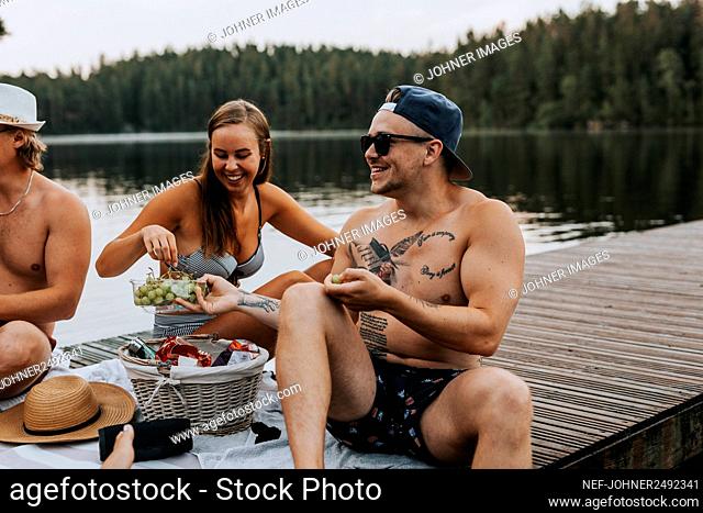 Happy friends having picnic on jetty