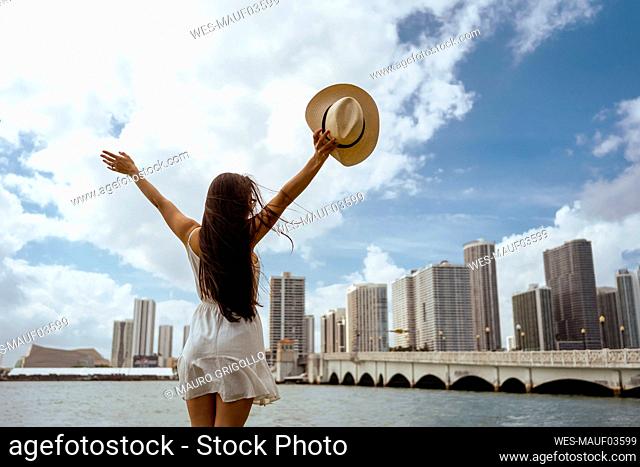 Young woman with arms outstretched standing in city