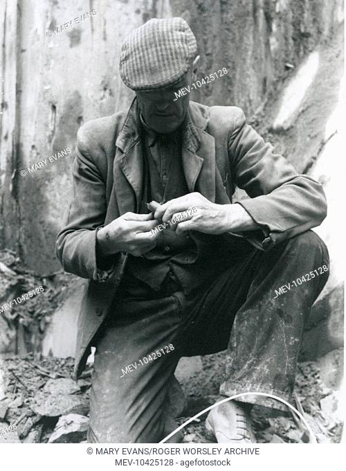 A workman fixing a detonator to a dynamite stick at Penyrorsedd Slate Quarry, Nantlle Valley, Caernarvonshire (now Gwynedd), North Wales