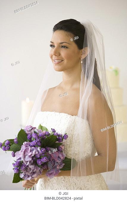 Hispanic bride holding bouquet of flowers