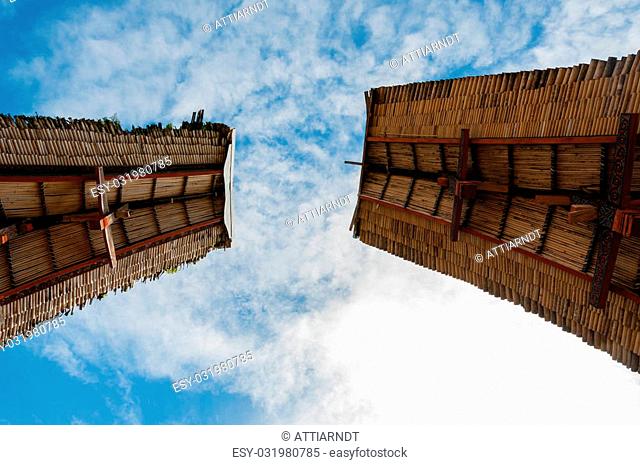 Two rooftops of traditional houses in Tana Toraja under blue cloudy sky, Sulawesi, Indonesia