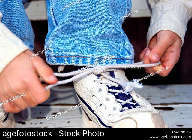 Four year old boy learning to tie shoe laces