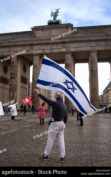 Berlin, Germany, Europe - A man waves an Israeli flag with the star of David at the Platz des 18 Maerz square in front of the Brandenburg Gate in Mitte district...