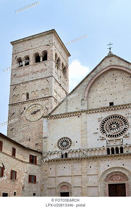 Detail view of Romanesque Duomo of Assisi, with square campanile tower, facade with rose window, stone carving decoration, Assisi, Umbria, Italy